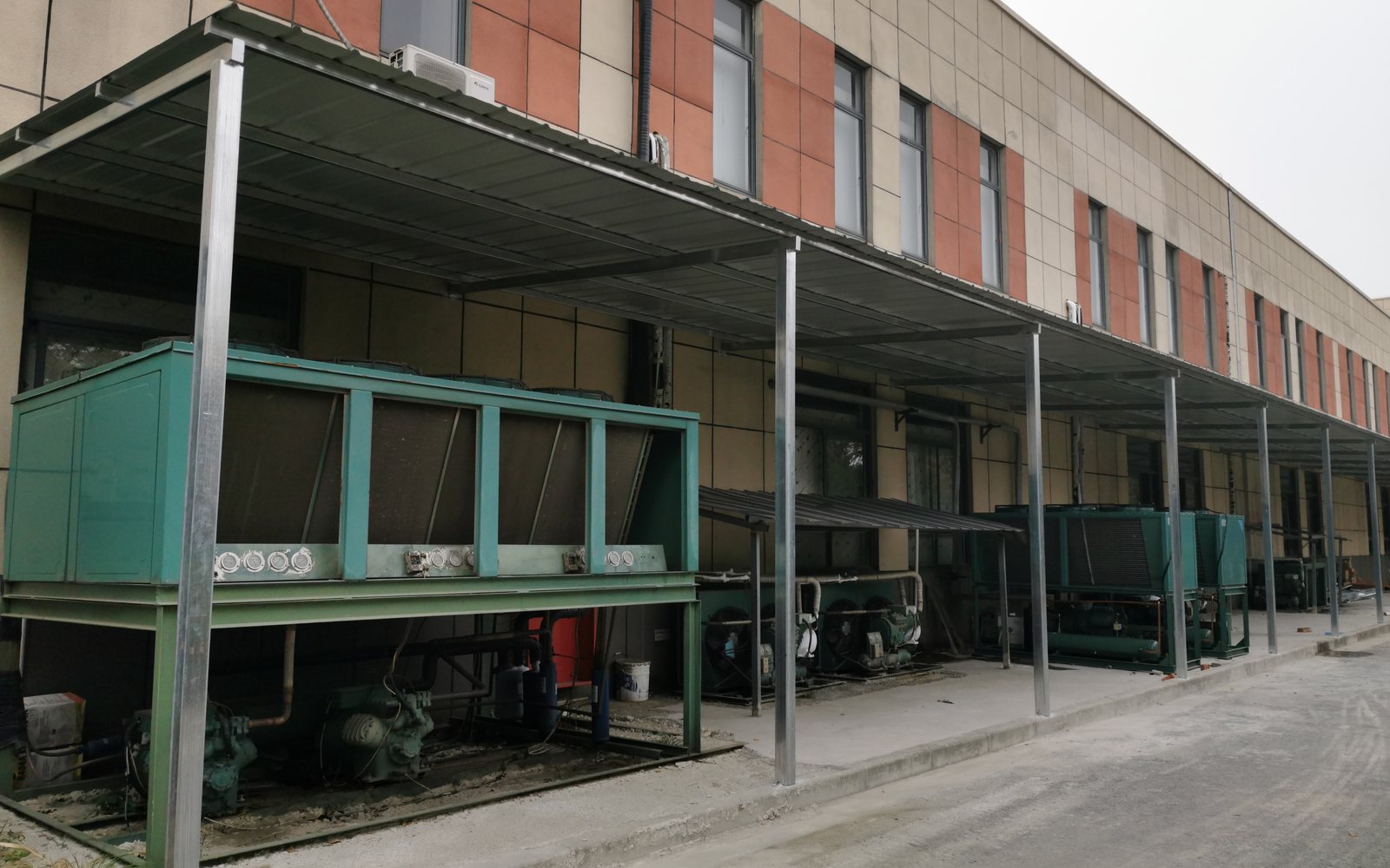 Cold storage refrigeration equipment yard beside an industrial building